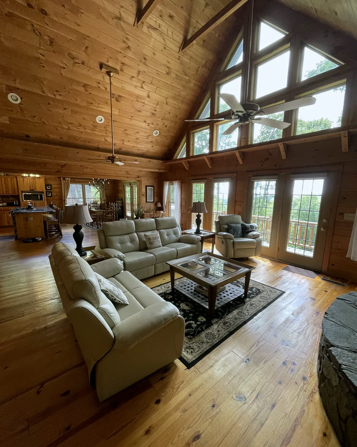 A mountain cabin living room with tall windows and pine walls, cleaned by Golden Bee
