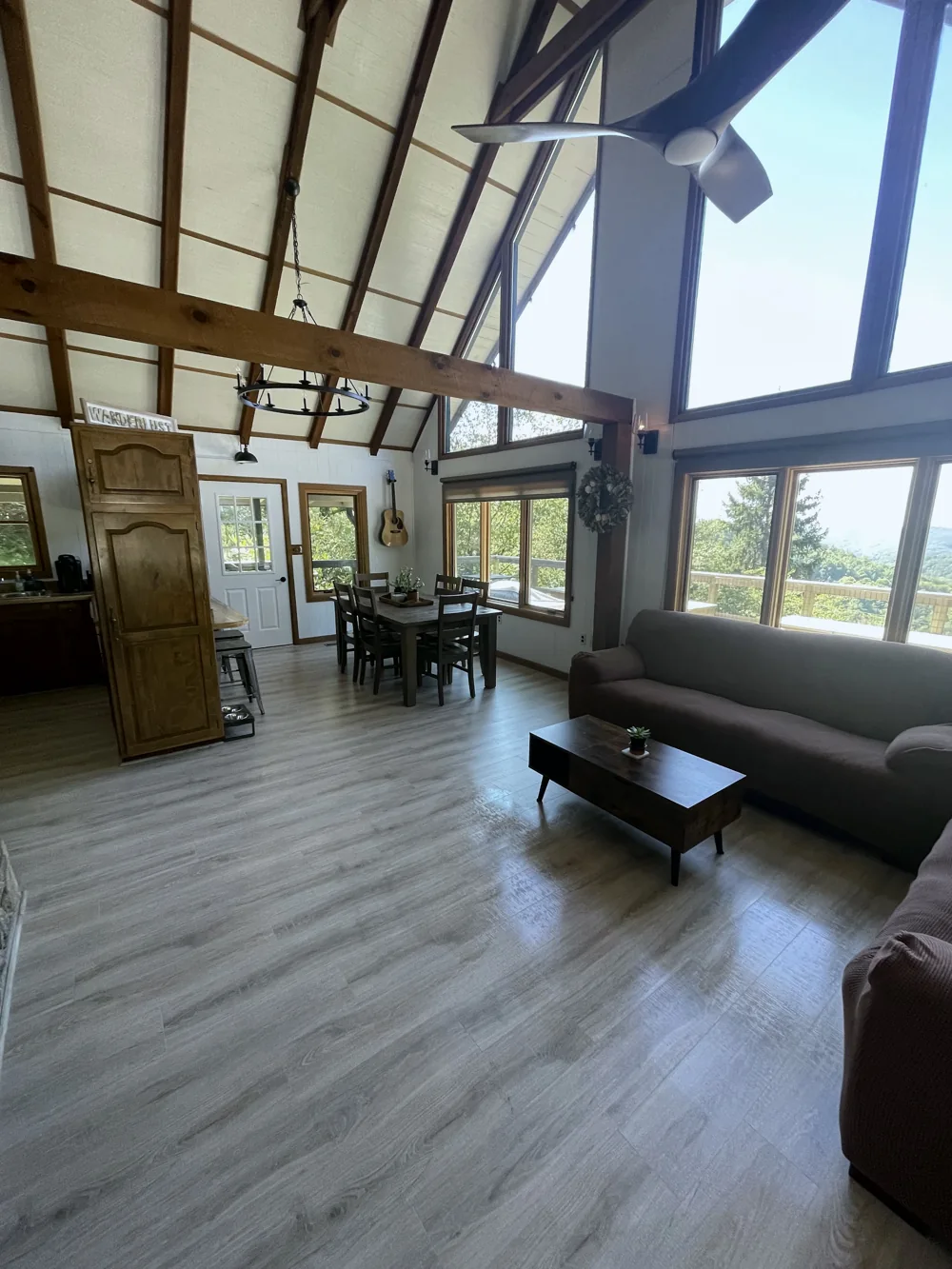 A-frame living room with tall windows, a sofa, and clear wood floors