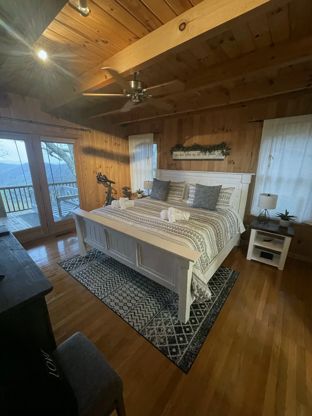 Made cabin bed with folded towels and French doors opening toward a deck