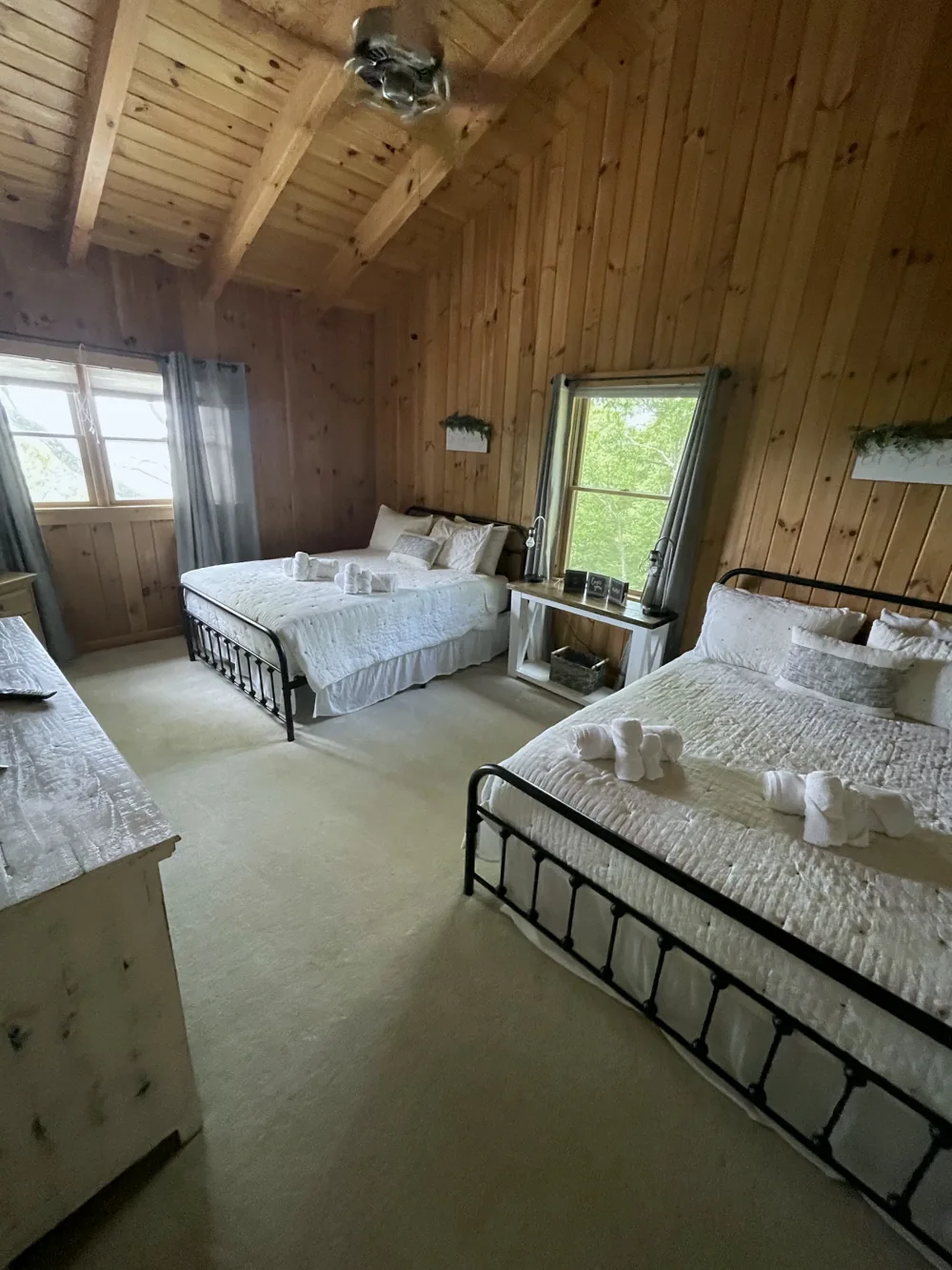 Cabin guest room with made beds and towels arranged on the bedding
