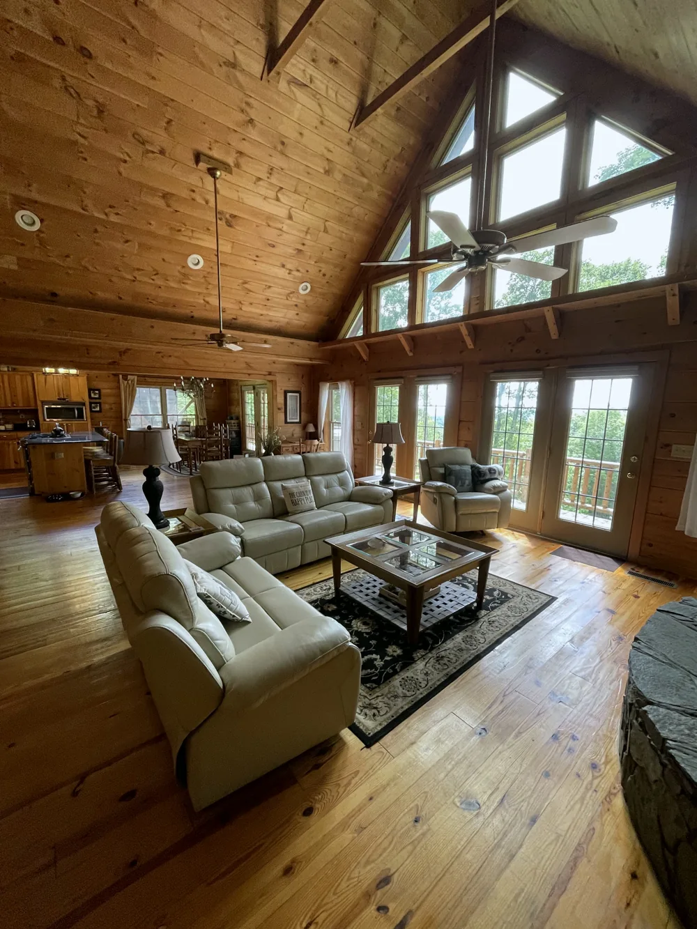 Cabin living room with tall windows, wood floors, and a vaulted ceiling