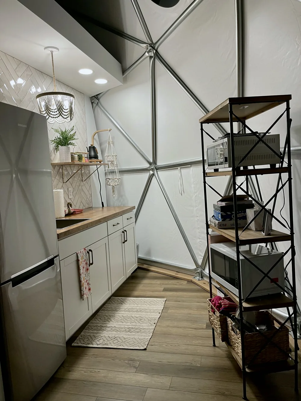 Compact dome kitchen with white cabinets, a refrigerator, and open shelving