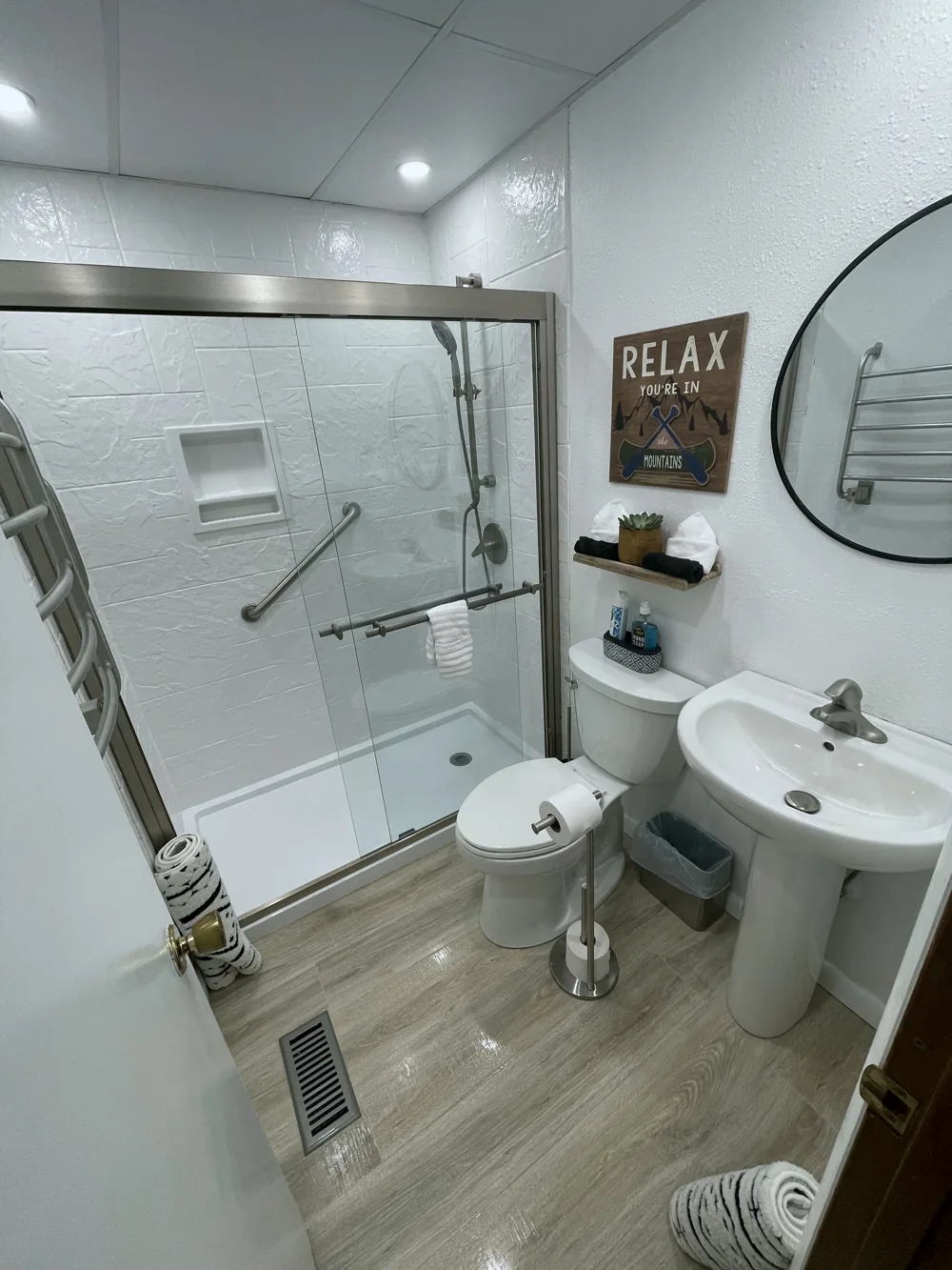 Bathroom with a glass shower, white tile, and a round mirror