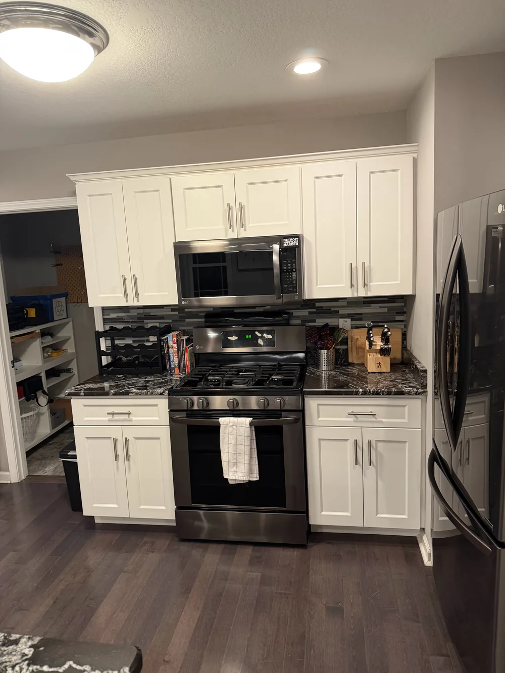 White kitchen cabinets, dark counters, and black appliances.